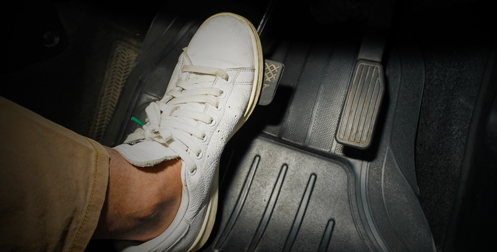 A person's feet resting on the car floor, illustrating the importance of checking brake pads for wear and tear