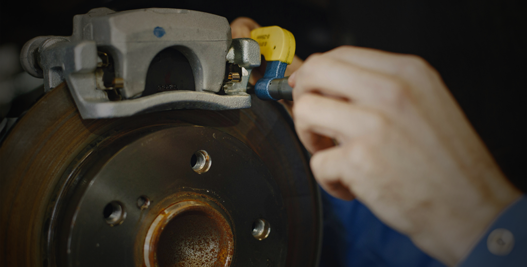A mechanic inspects brake pads while fixing a brake disc on a car, ensuring optimal performance and safety