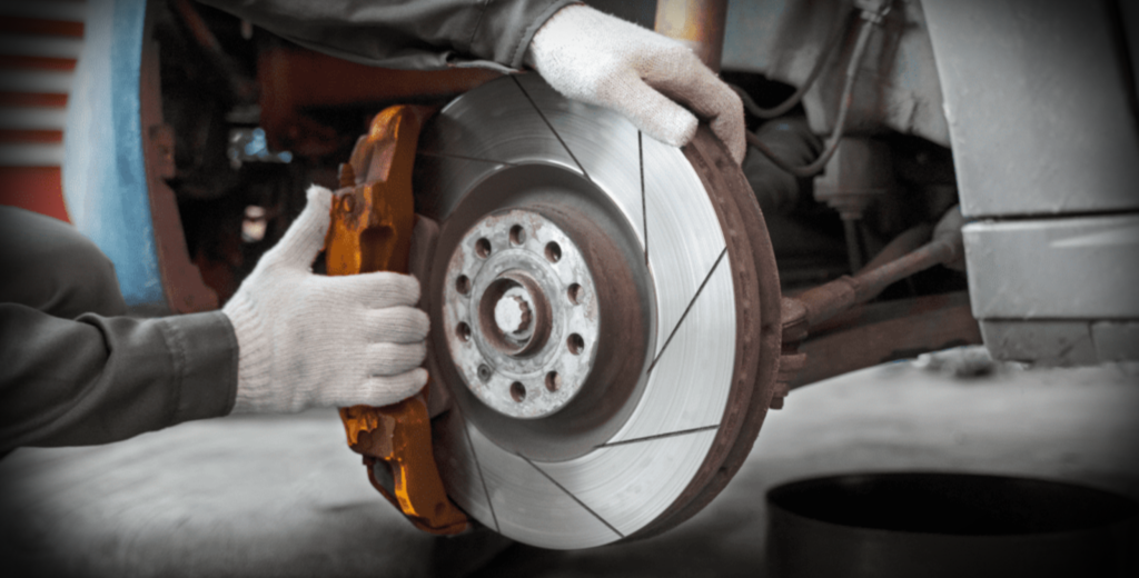 A technician carefully inspects a brake disc while preparing to change the brake pads on a vehicle.