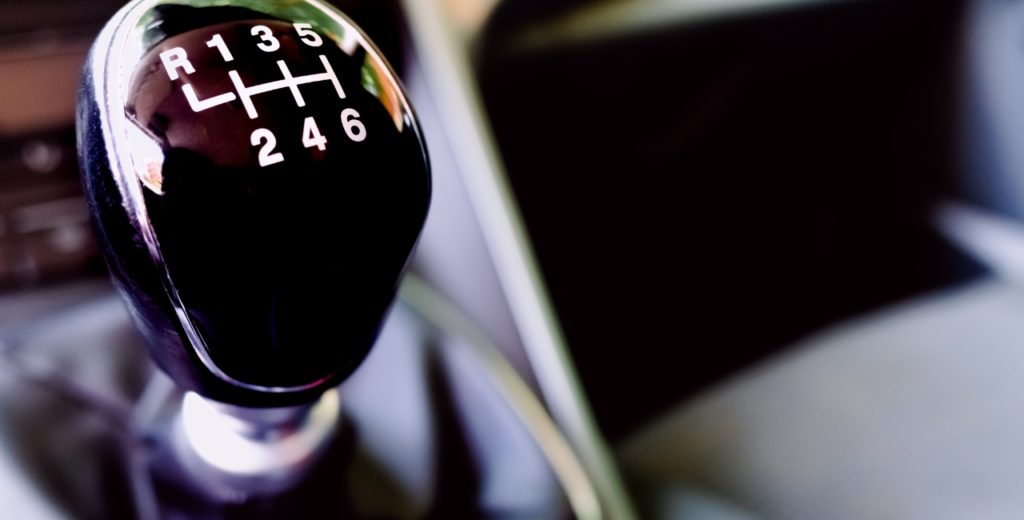 Close-up of a manual transmission gear shift in a car, showcasing its intricate design and functional elements.