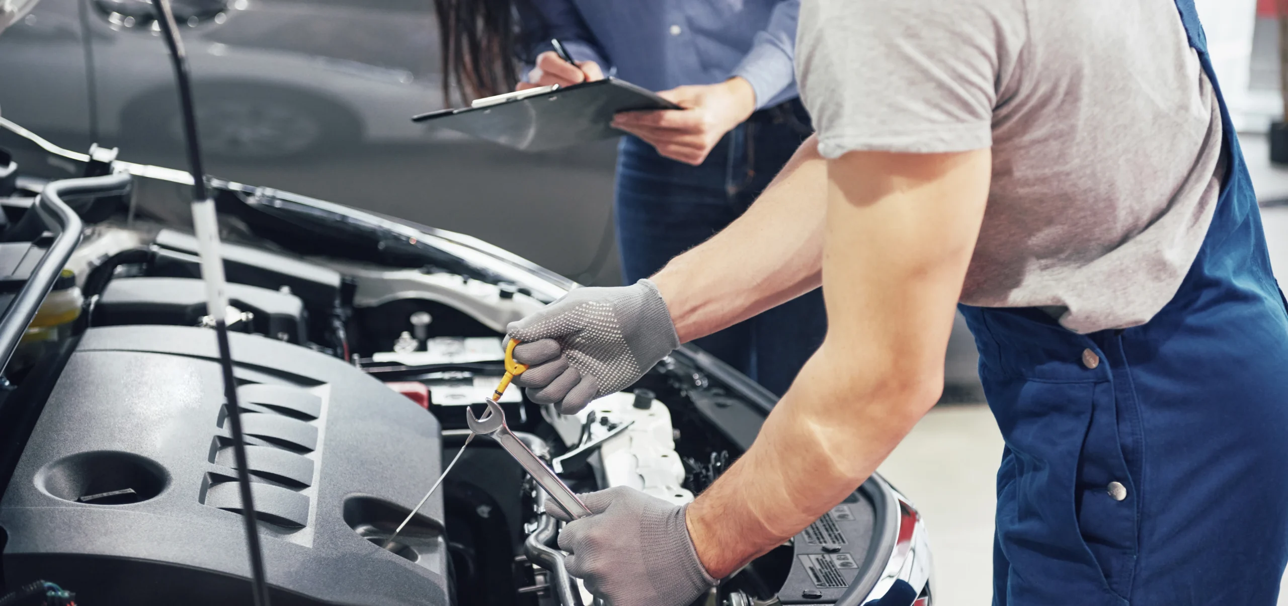 A man and woman engaged in car repair work in Houston, demonstrating teamwork on an automotive project.
