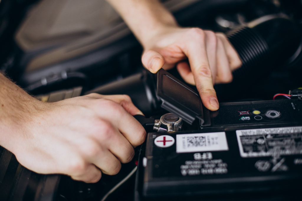 A person inspecting and working on a car battery, focusing on maintenance and replacement timing.
