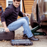 A man using a tool to fix a flat tire, demonstrating the process of changing a tire.