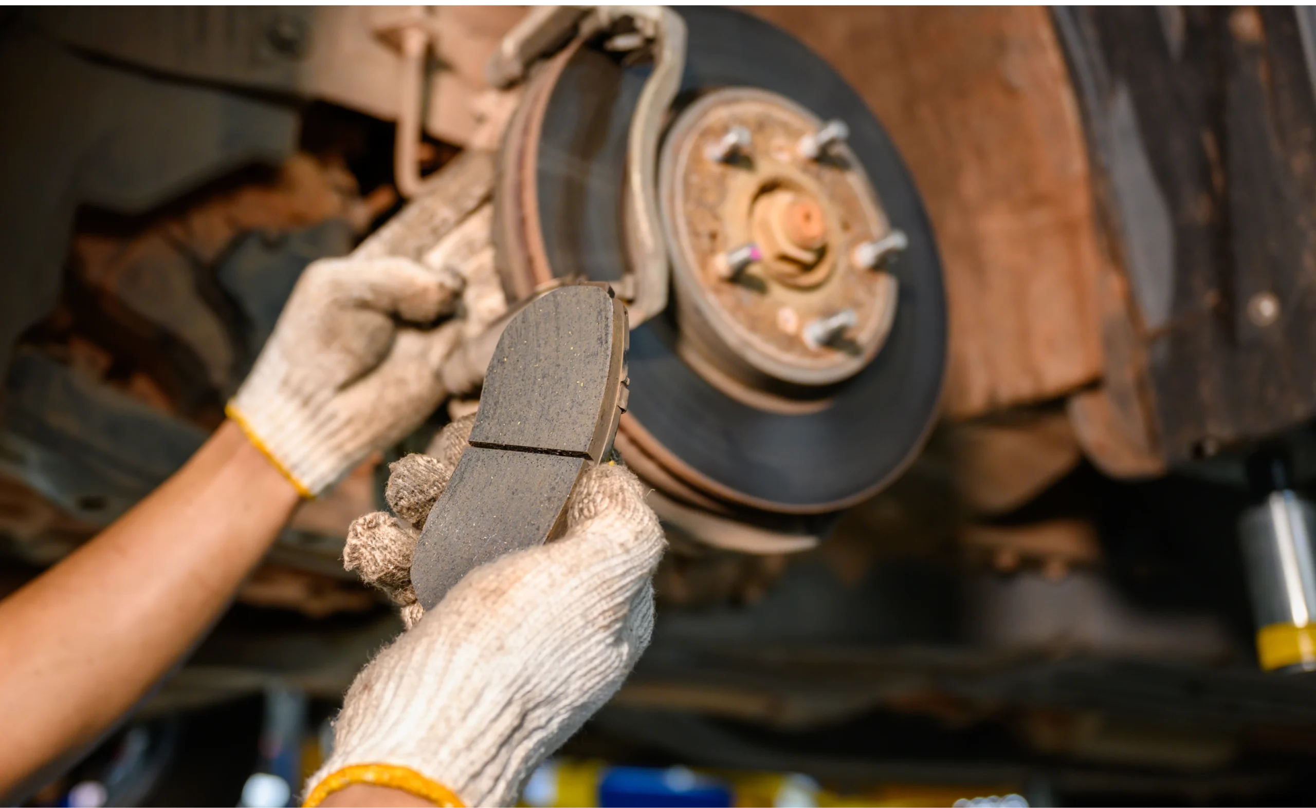 A person wearing gloves holds a brake disc, representing brake repair services in Houston.