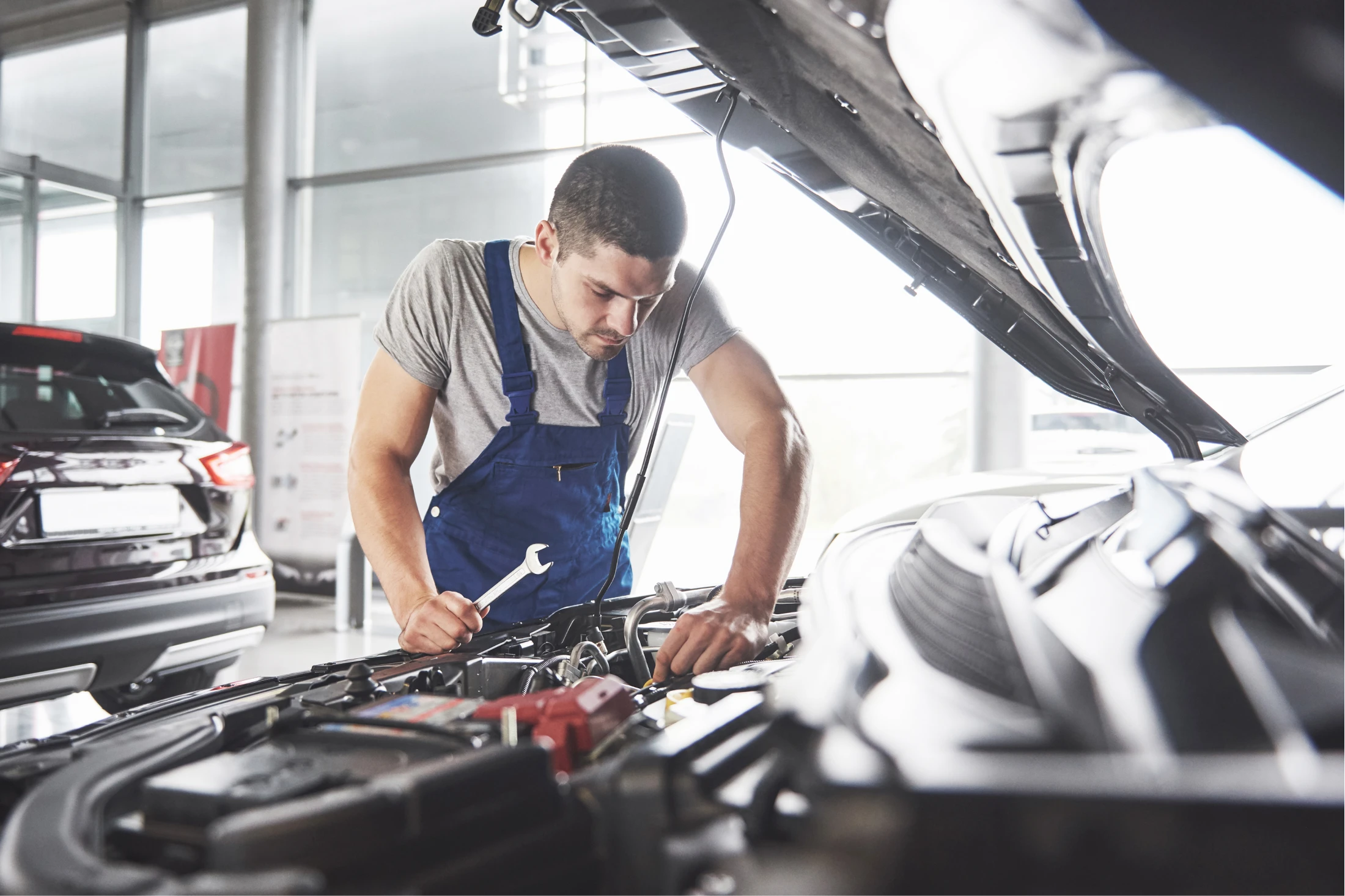 A man is engaged in car maintenance inside a garage, representing auto repair services in Houston.