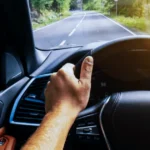 Driver holding steering wheel while car shakes on road