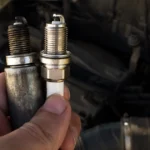Mechanic comparing old and new spark plugs for rough idle