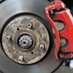 A close-up shot of a car's disc brake and red caliper.