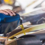 Mechanic pouring synthetic oil into a car engine during maintenance.