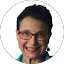 A woman with glasses in a blue shirt smiles while giving reviews at Eric's Car Care.