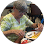 An older woman enjoying breakfast at a table, providing reviews for Eric's Car Care.