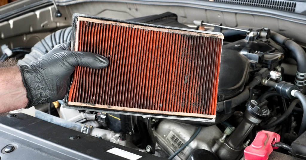 Mechanic replacing dirty engine air filter in car