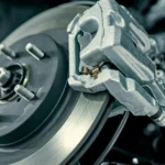 Detailed view of a modern disc brake assembly, including the silver caliper, rotor, and suspension spring.