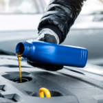 Close-up of a blue oil bottle pouring engine oil into a car engine.