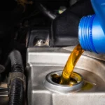 Golden motor oil being poured into a car engine.