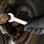 Mechanic using a wrench on the car suspension.