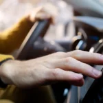 A mechanic carefully cleaning a mass air flow sensor with specialized cleaner