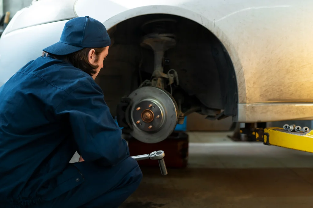 A mechanic inspecting a brake master cylinder under the hood of a vehicle