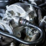 Close-up view of a metal car engine component with connected black hoses.
