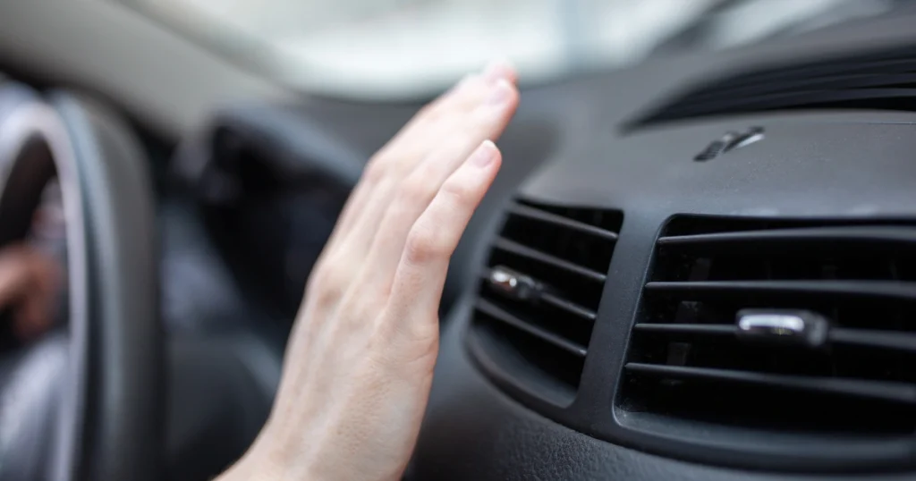 Hand checking car heater blowing cold air