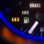A close-up view of a car dashboard showing illuminated ABS and warning lights